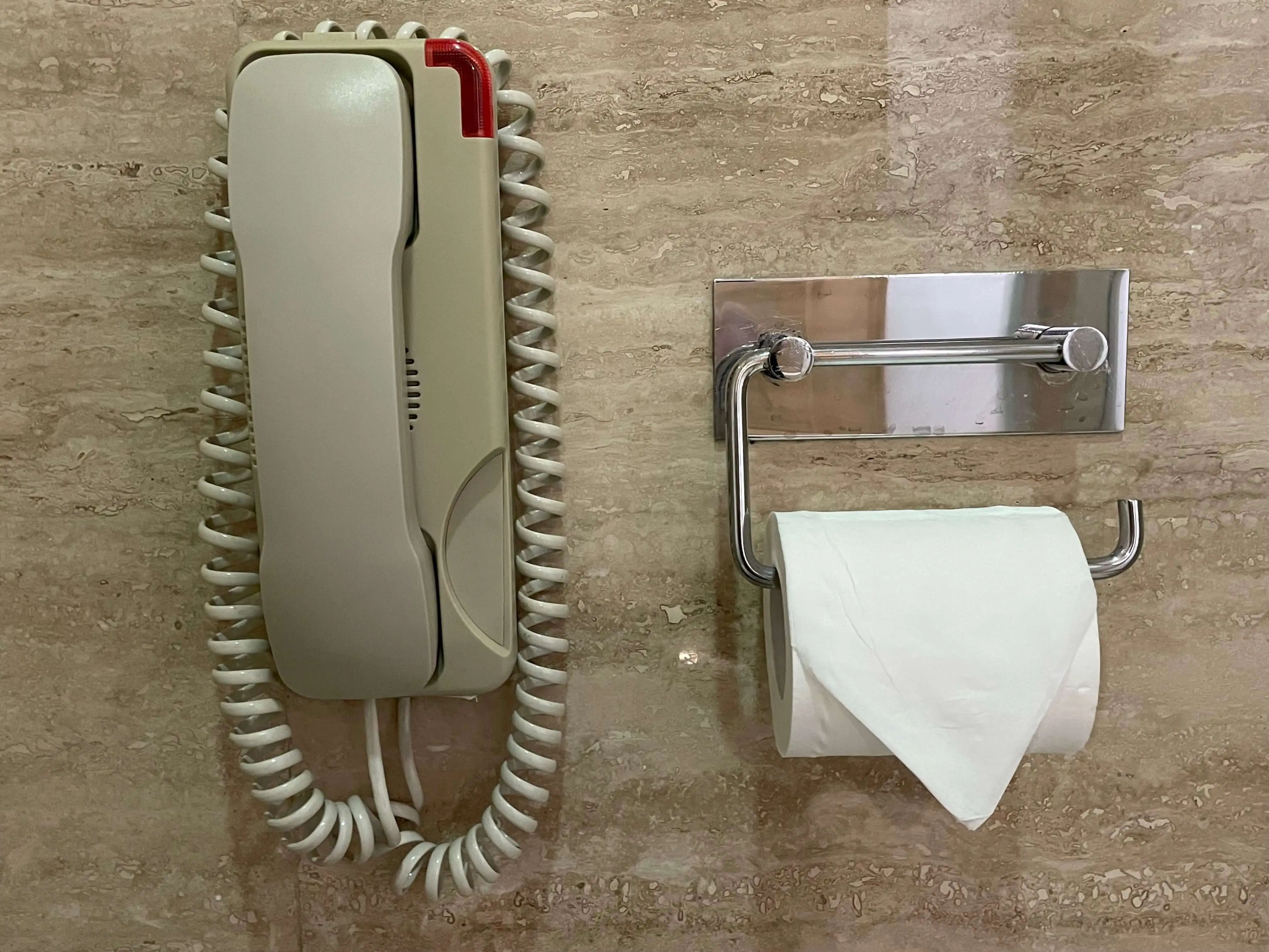 Hotel bathroom telephone mounted beside a toilet roll holder